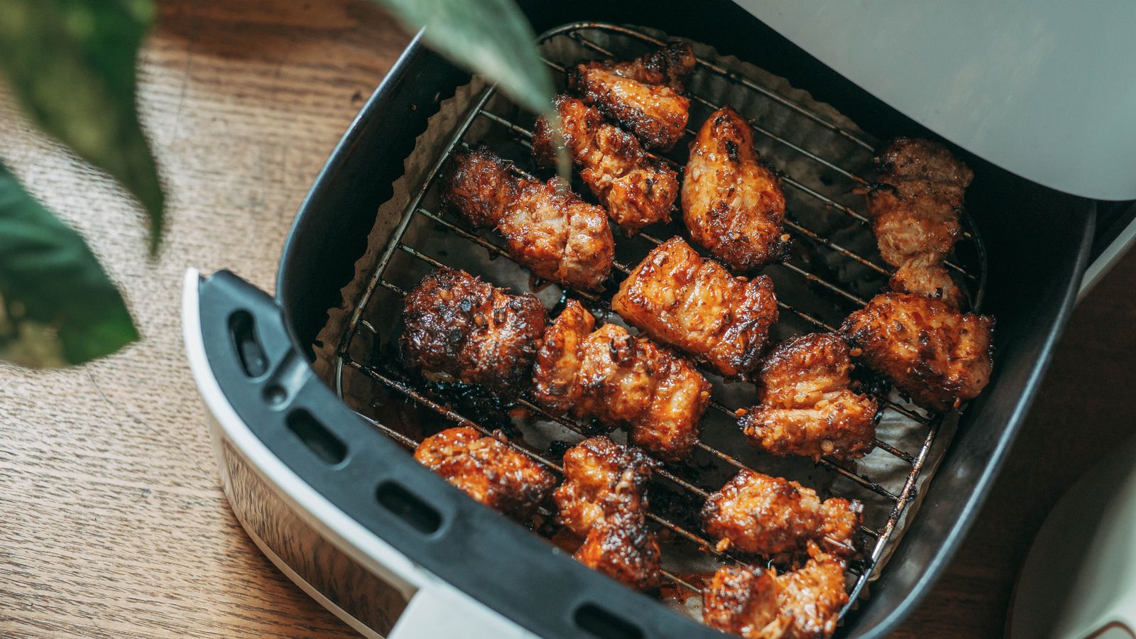 Crispy chicken pieces cooking in an air fryer basket