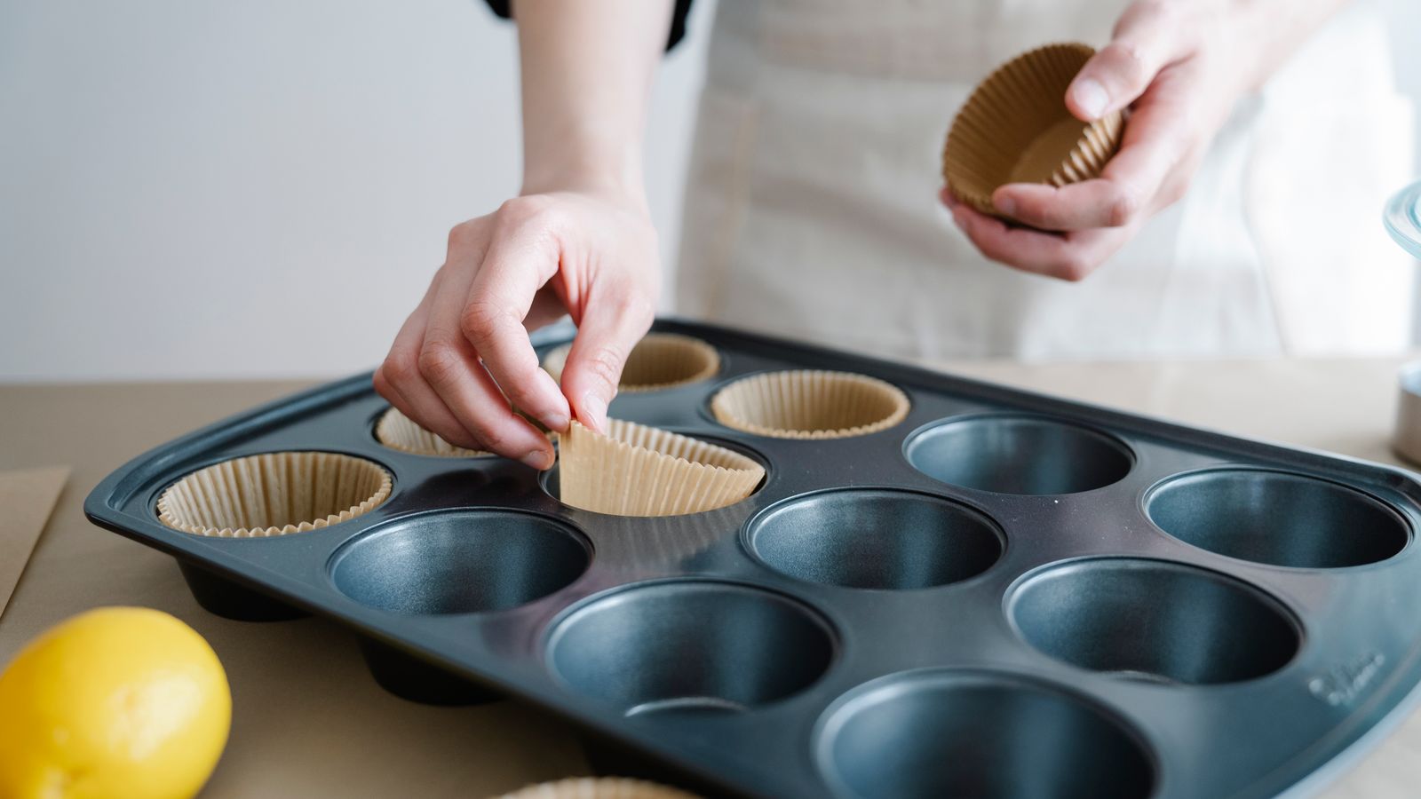 Silicone baking cups being placed into an air fryer tray for muffins