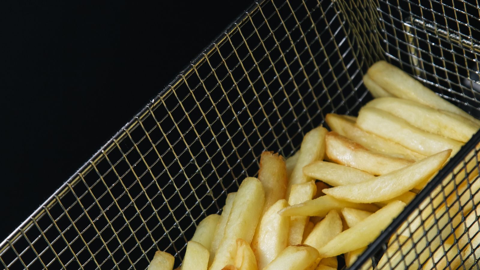 Air fryer basket with mesh accessory tray showing food residue that needs cleaning