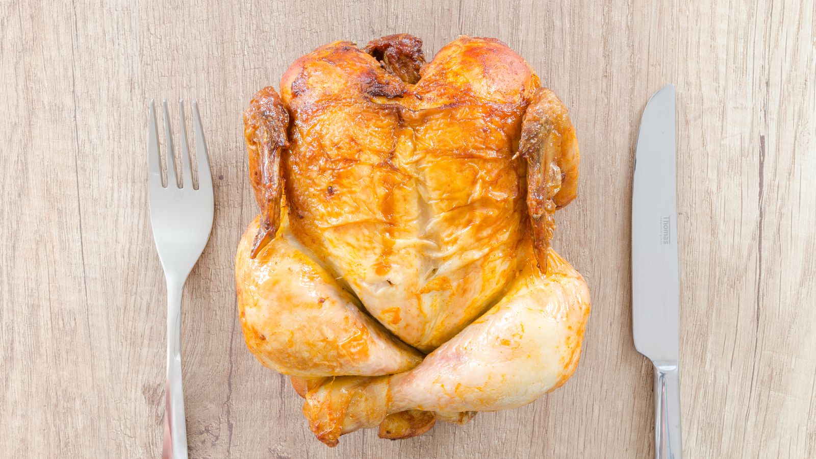 A whole rotisserie chicken resting on a spit, representing the type of cooking an air fryer rotisserie kit is designed for