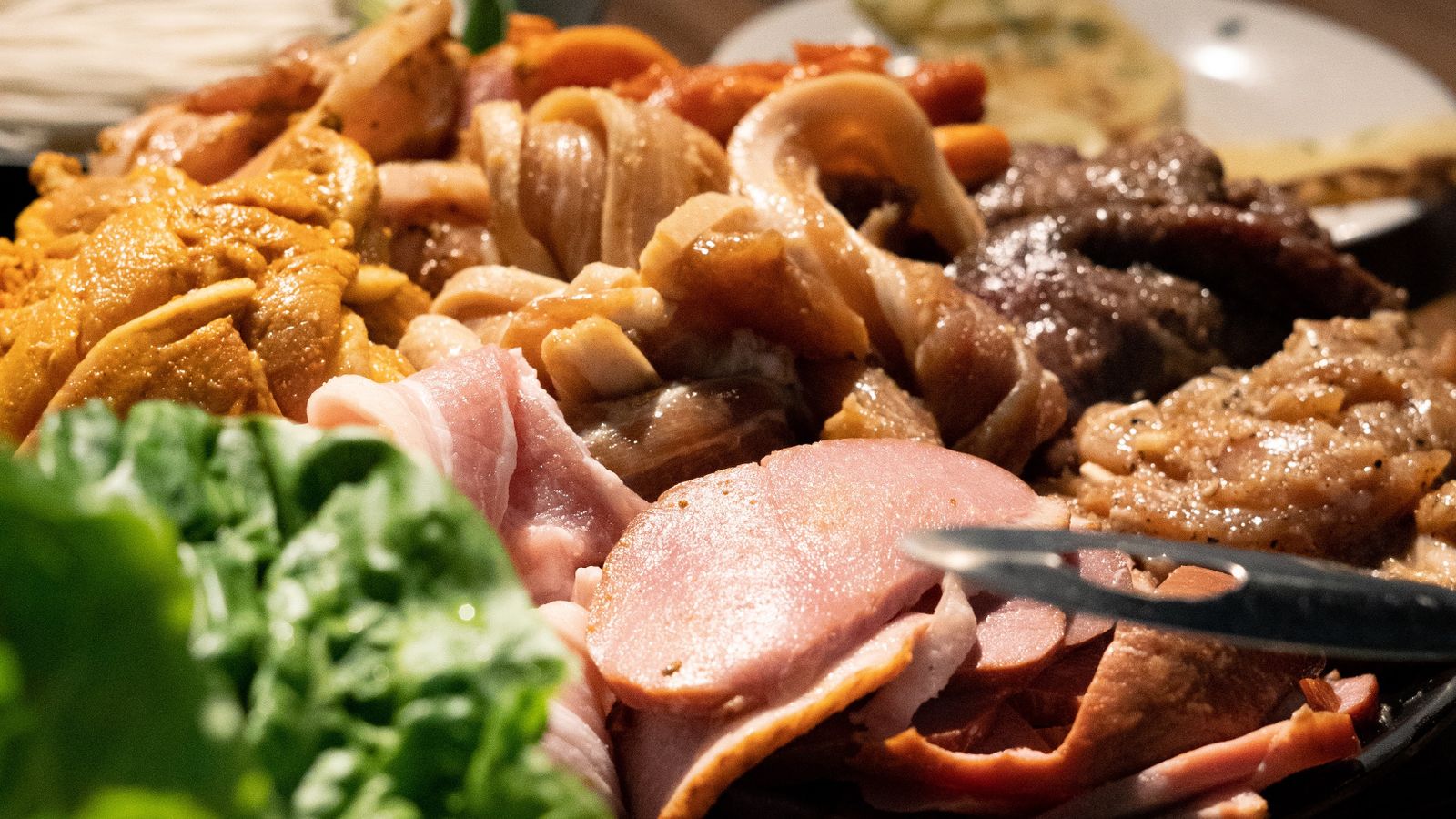 Seasoned vegetables and sliced meat arranged in an air fryer basket before cooking