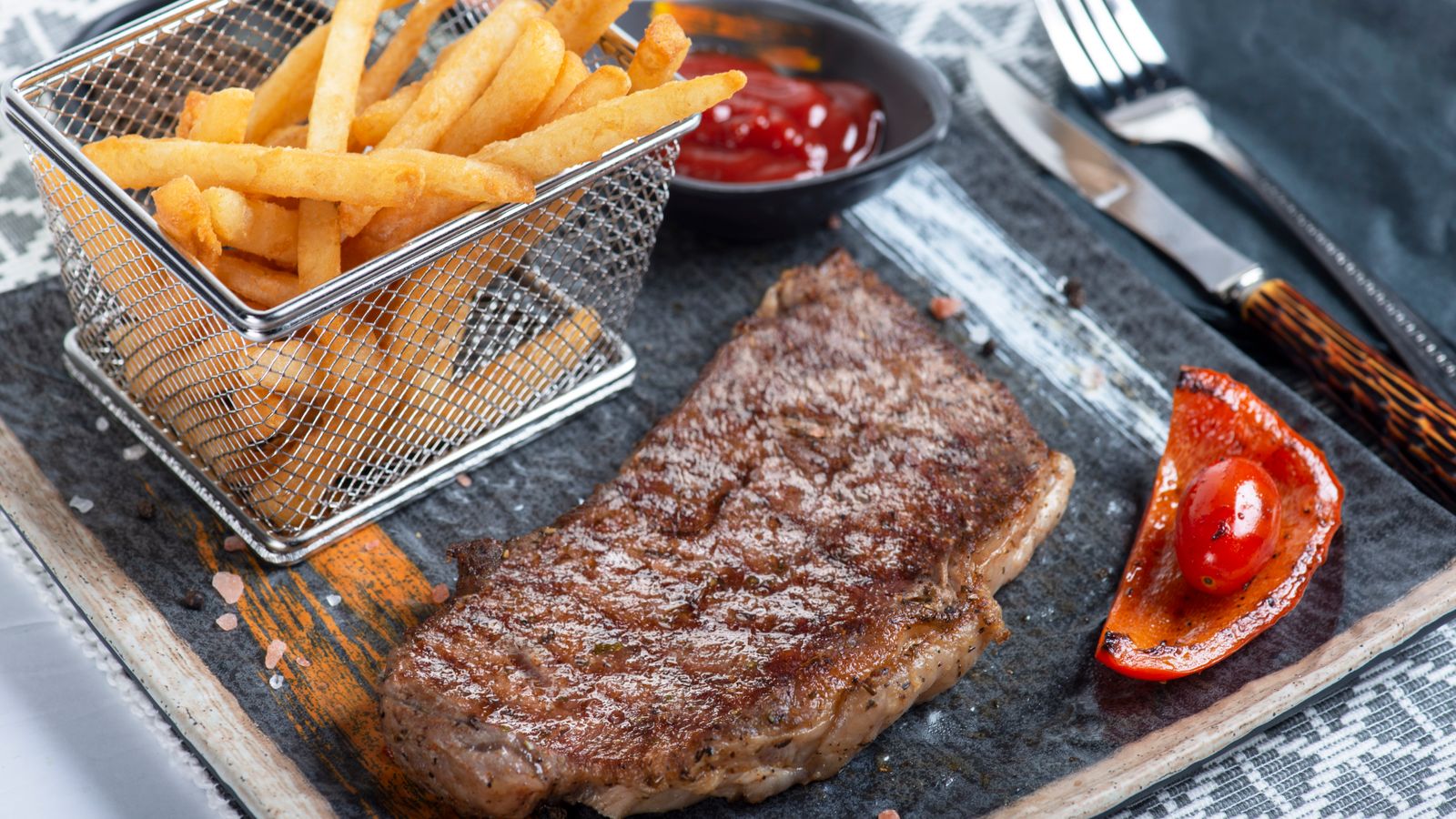 A seared steak fresh out of an air fryer basket with a browned crust