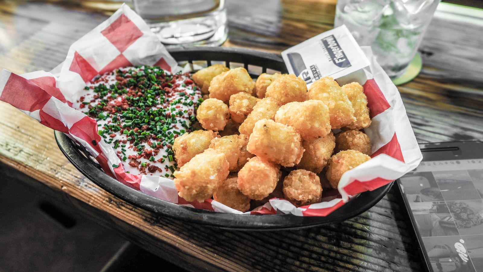 Crispy golden tater tots in an air fryer basket with dipping sauce