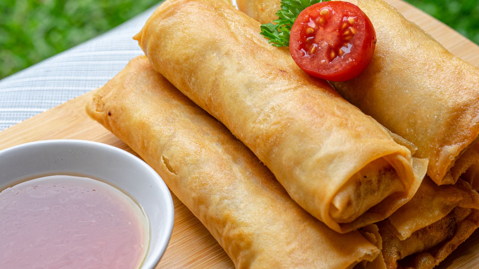 Crispy egg rolls arranged on a plate with dipping sauce