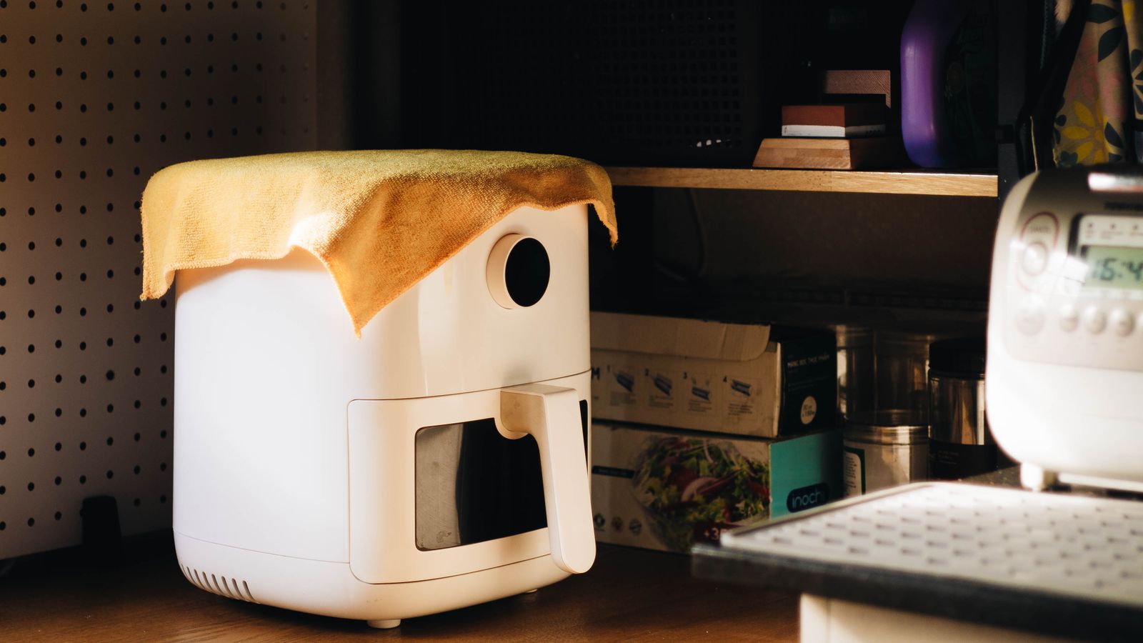 Compact air fryer sitting on a kitchen countertop near other appliances
