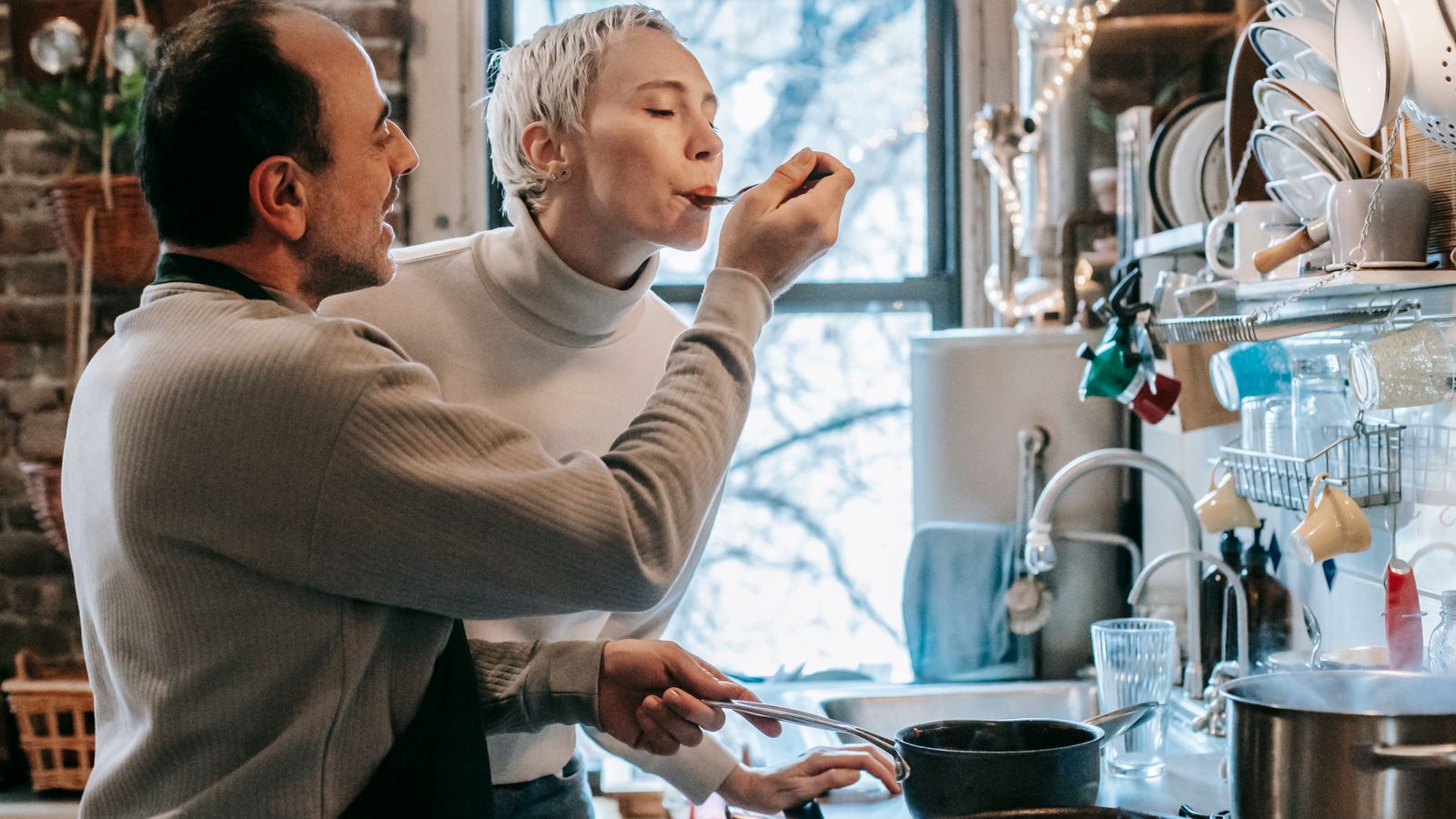 A couple cooking together in a small kitchen with a compact air fryer on the counter