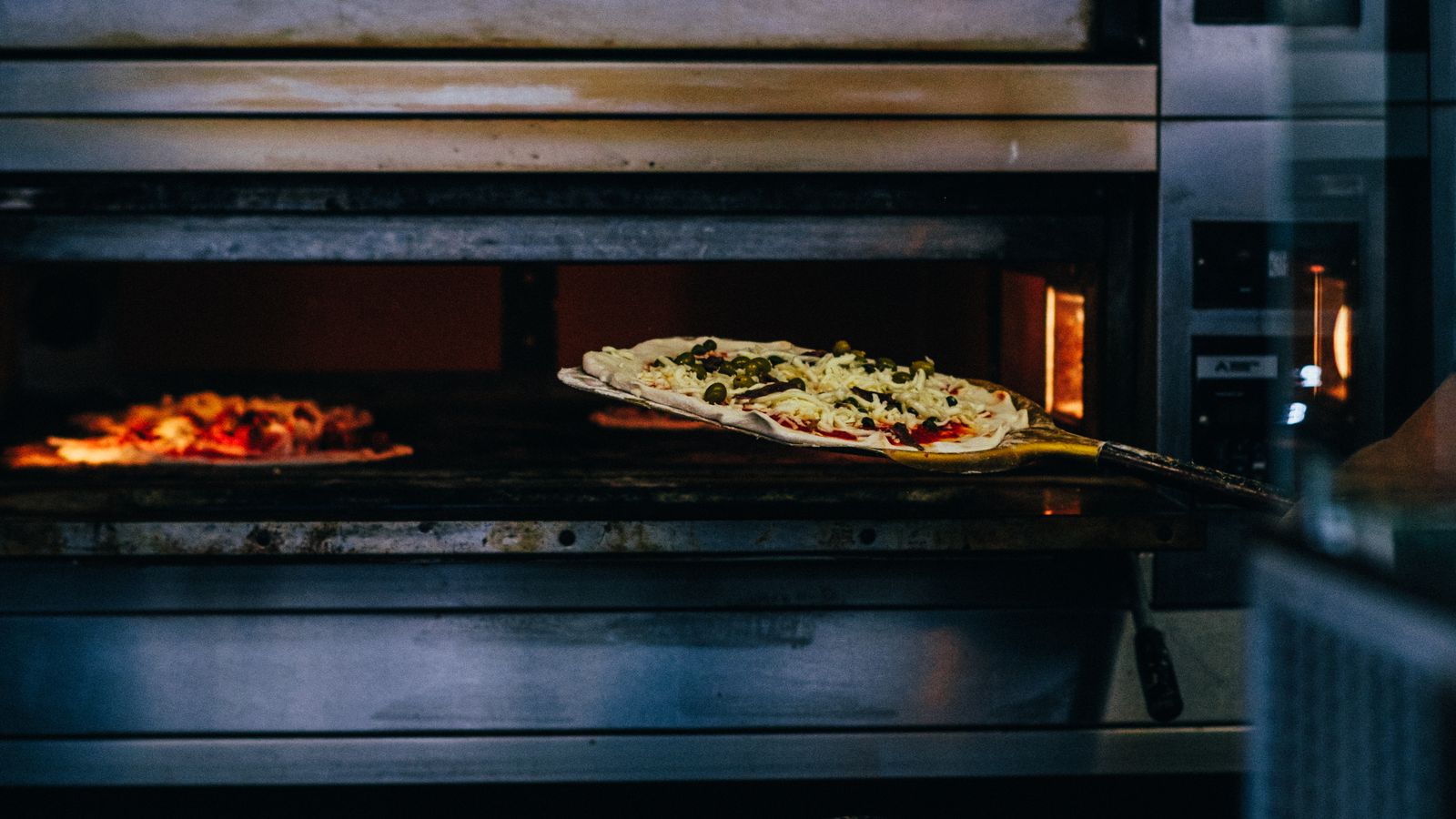 A well-seasoned baking steel fresh out of the oven with a golden crust pizza