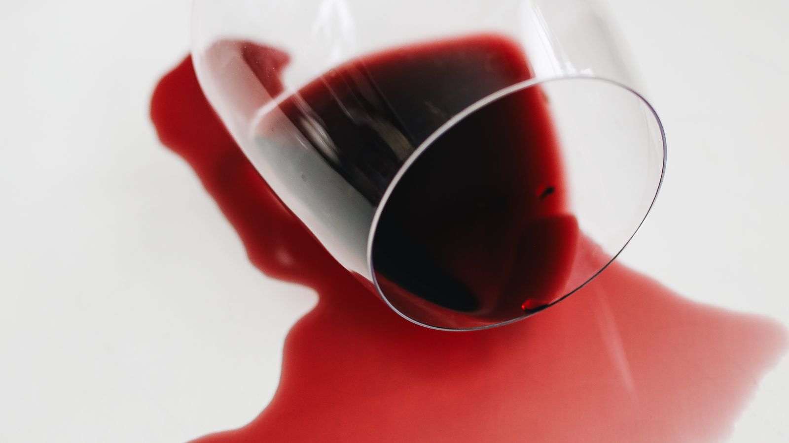 Fresh red wine spill soaking into a light-colored carpet fiber