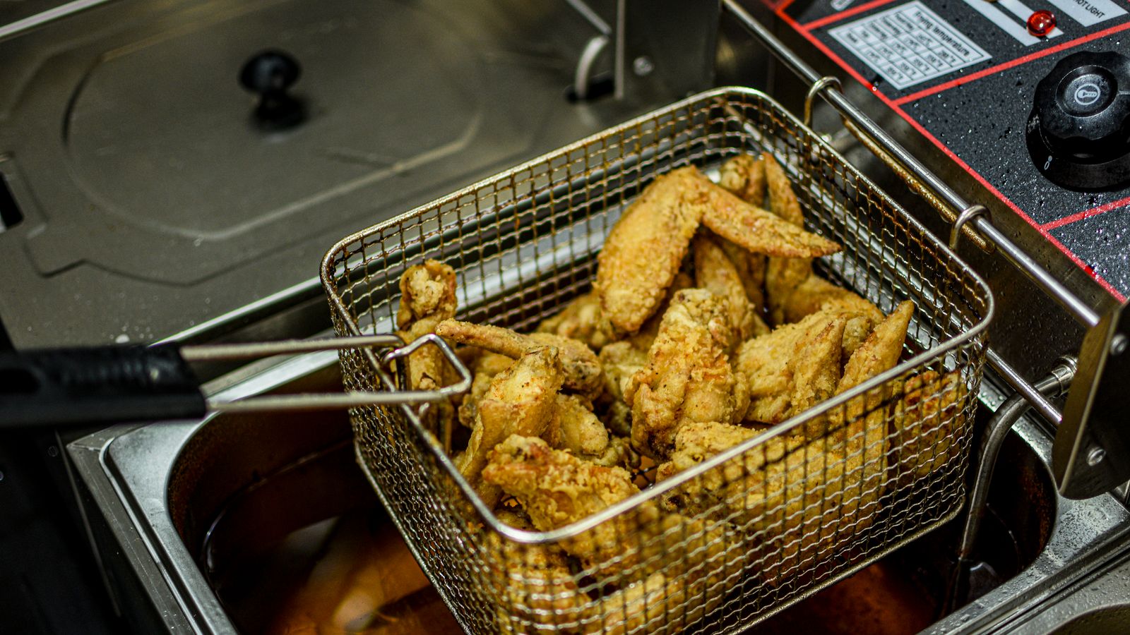 Golden brown chicken wings freshly cooked in an air fryer basket