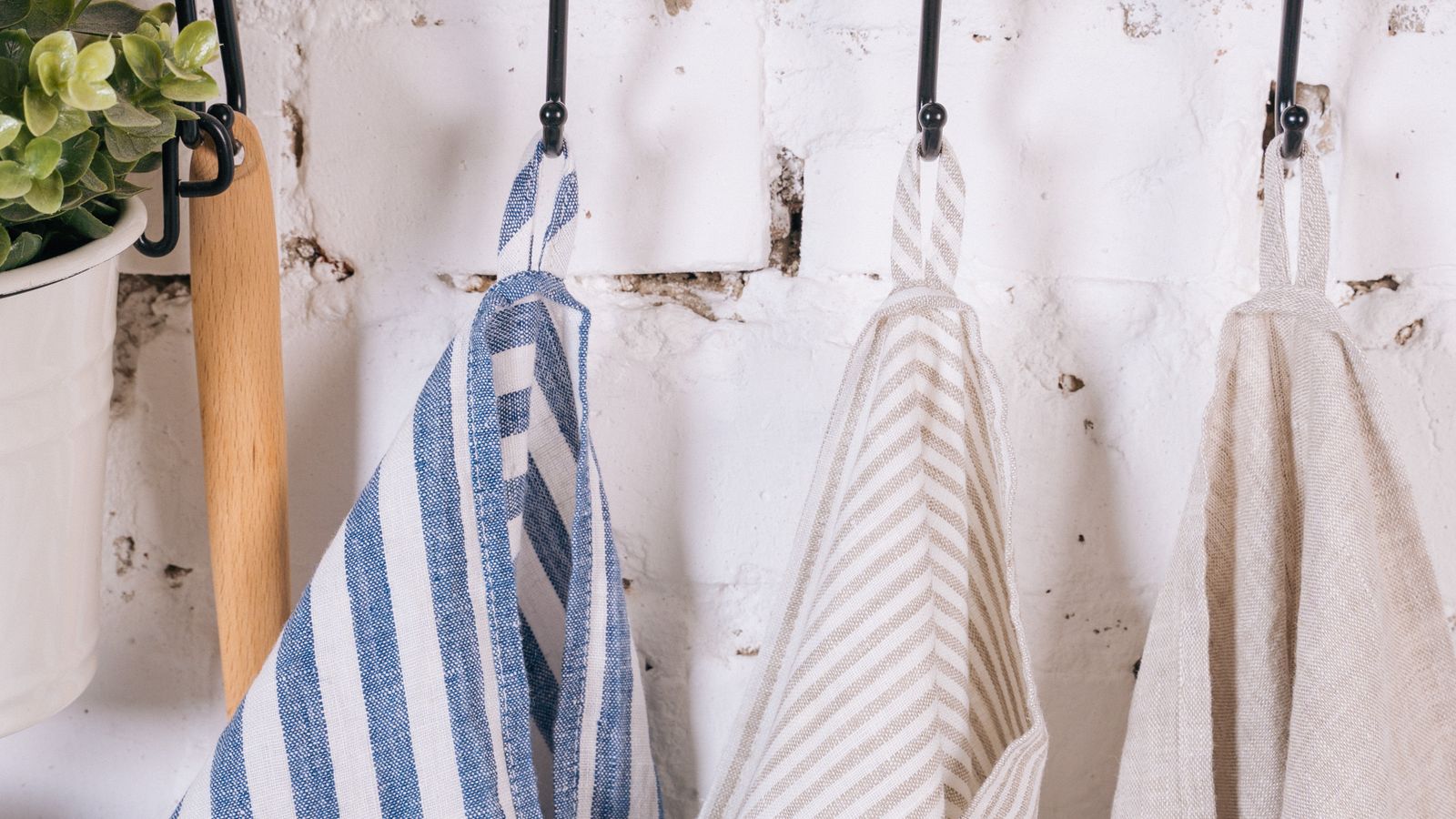Folded kitchen towel hanging on a wall-mounted hook near a countertop workspace