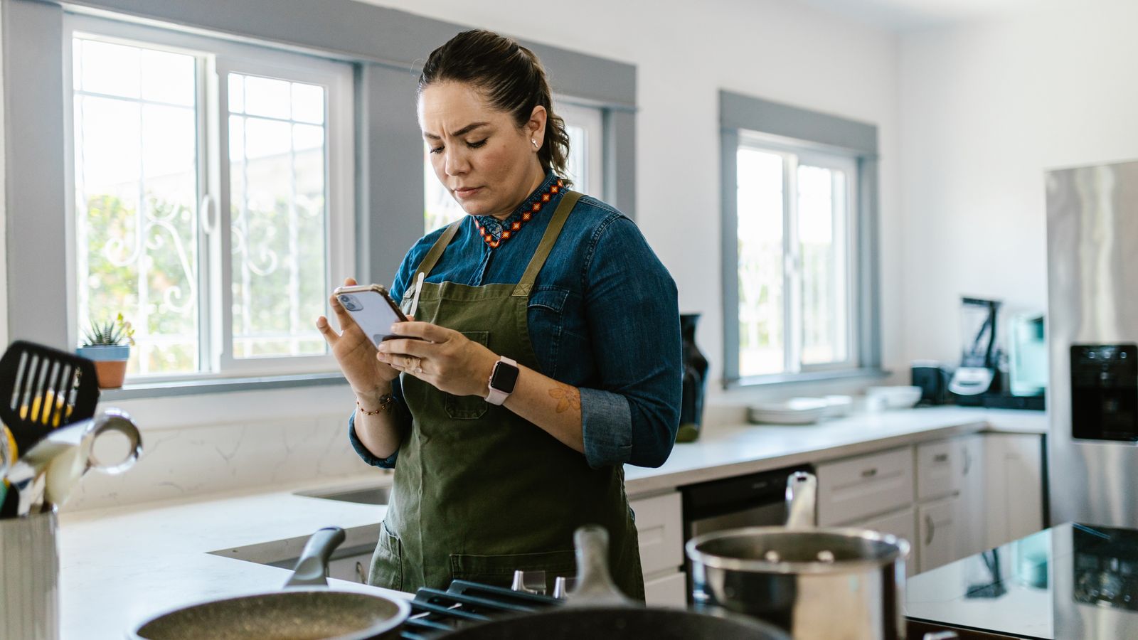Person checking a recipe on a smartphone app in a kitchen