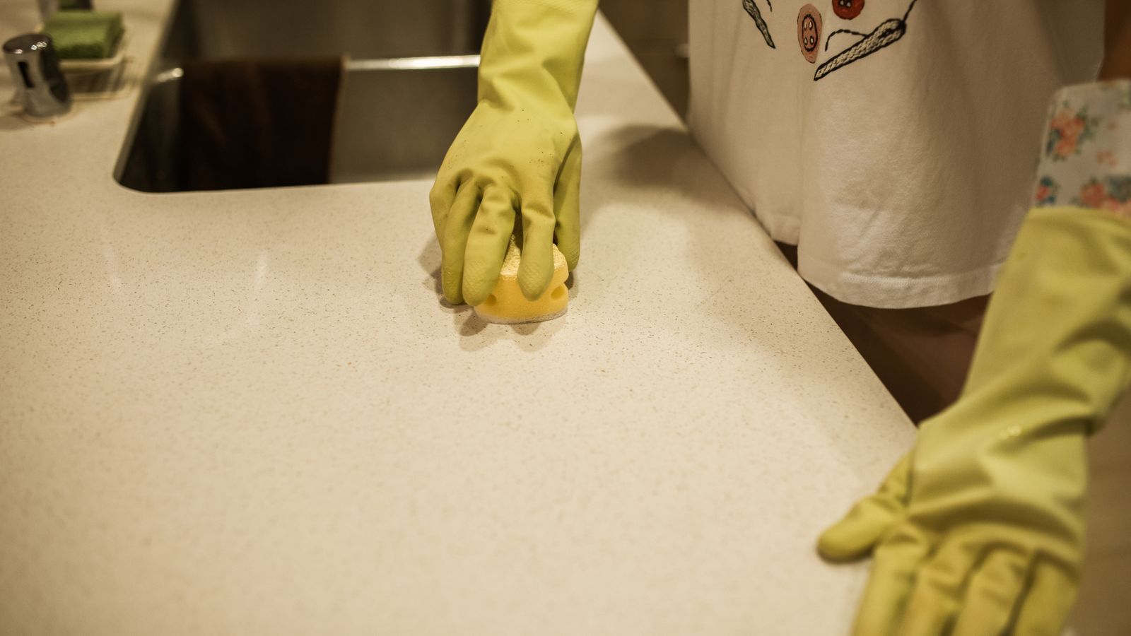 Hands wiping down a kitchen counter surface with a soapy cloth