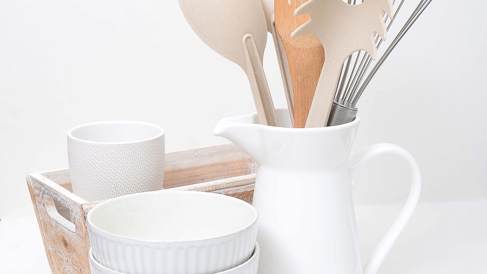 Neutral-toned wooden kitchen utensils and accessories arranged on a countertop