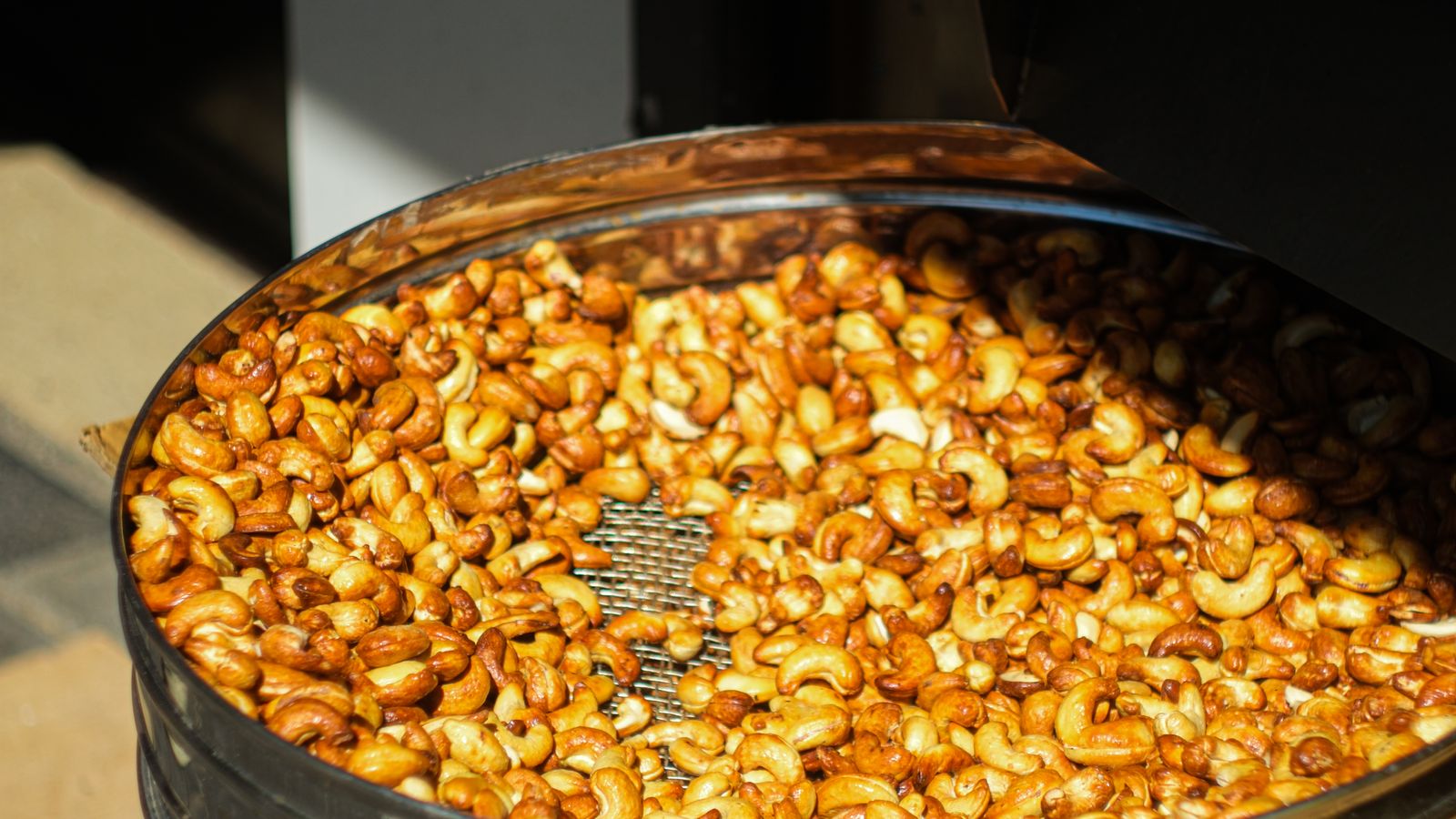 Bowl of freshly roasted mixed nuts next to an air fryer basket
