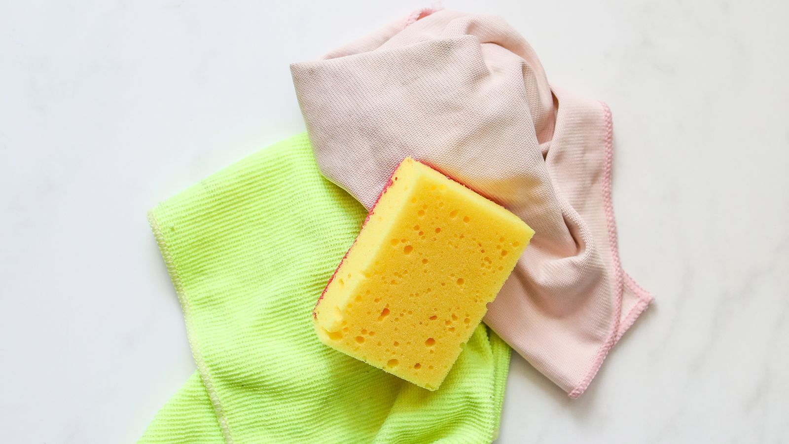 Hands scrubbing a metal kitchen rack with a soapy sponge in a sink