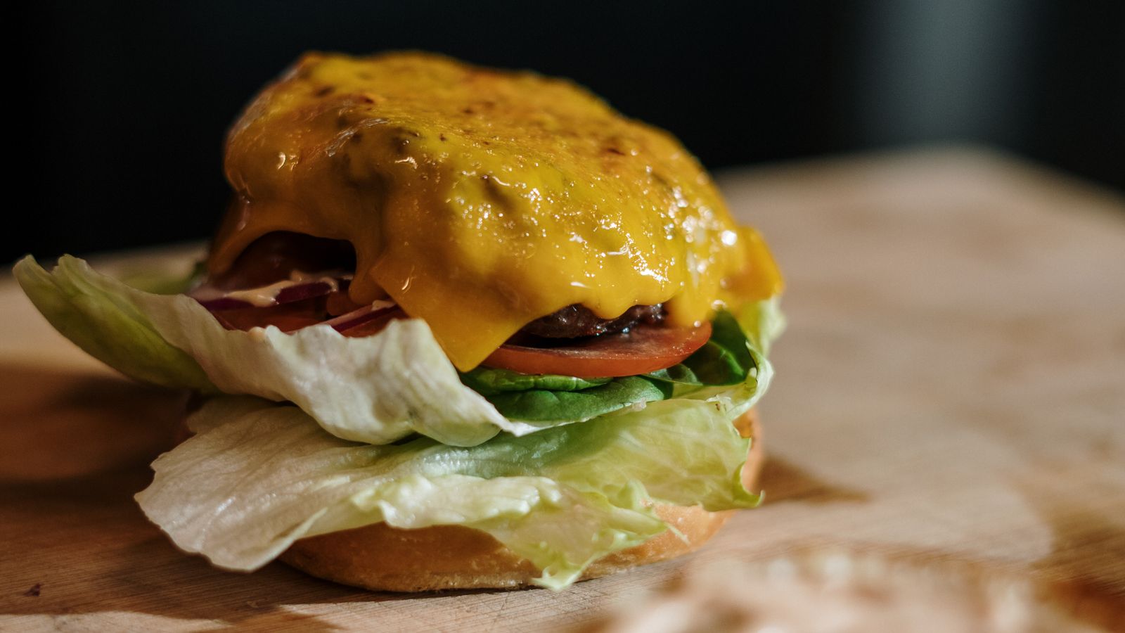 Close-up of a juicy air fryer cheeseburger with melted cheese and fresh toppings