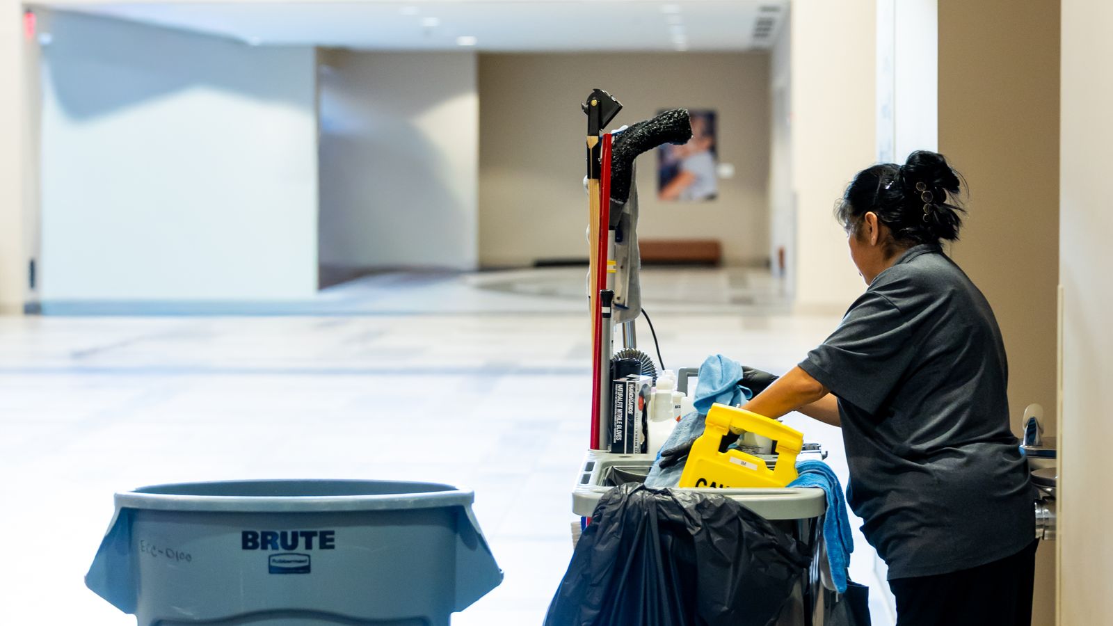 Janitorial cleaning cart loaded with commercial cleaning equipment in a hallway