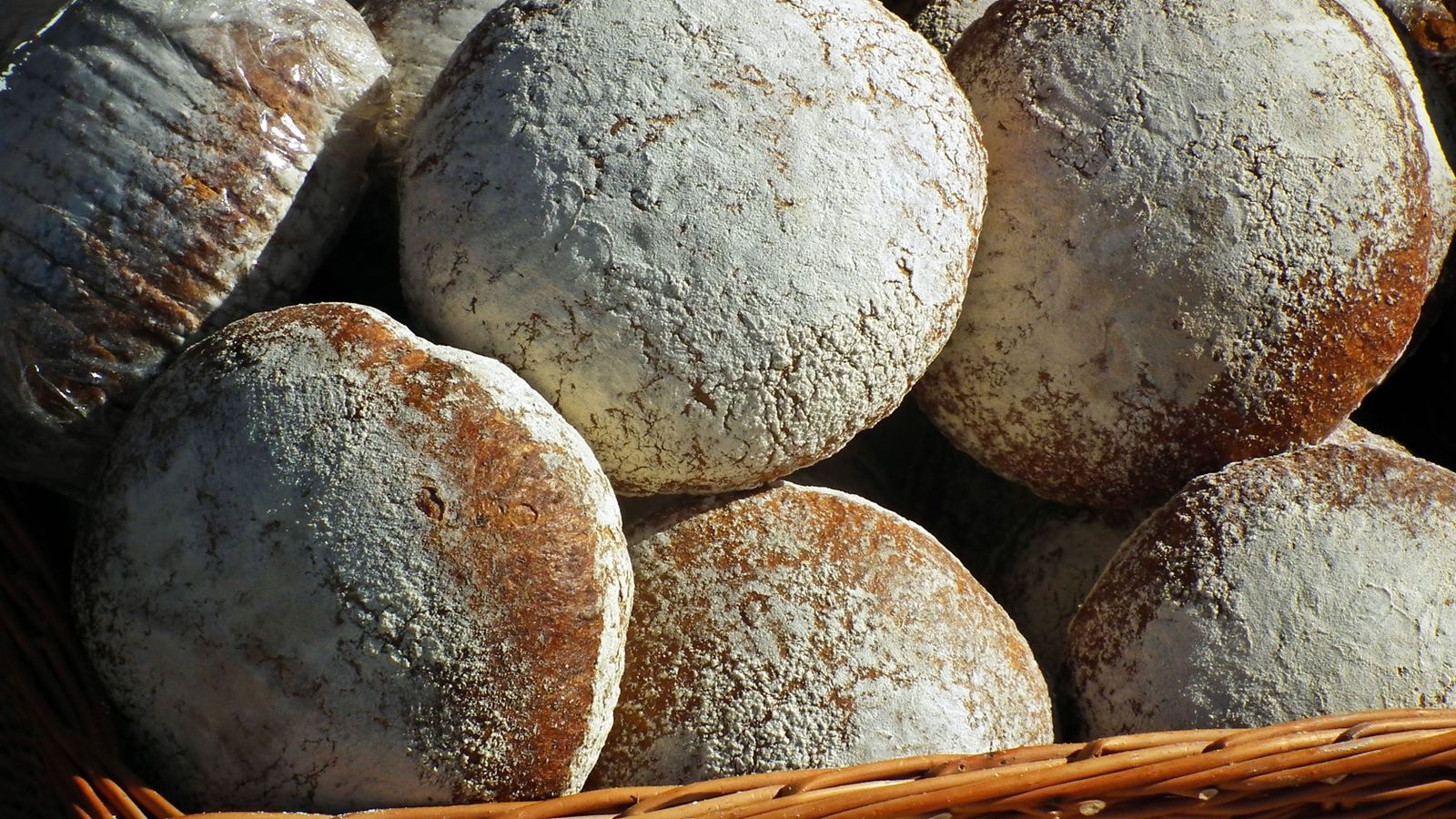 Fresh baked bread loaves cooling on a wooden surface