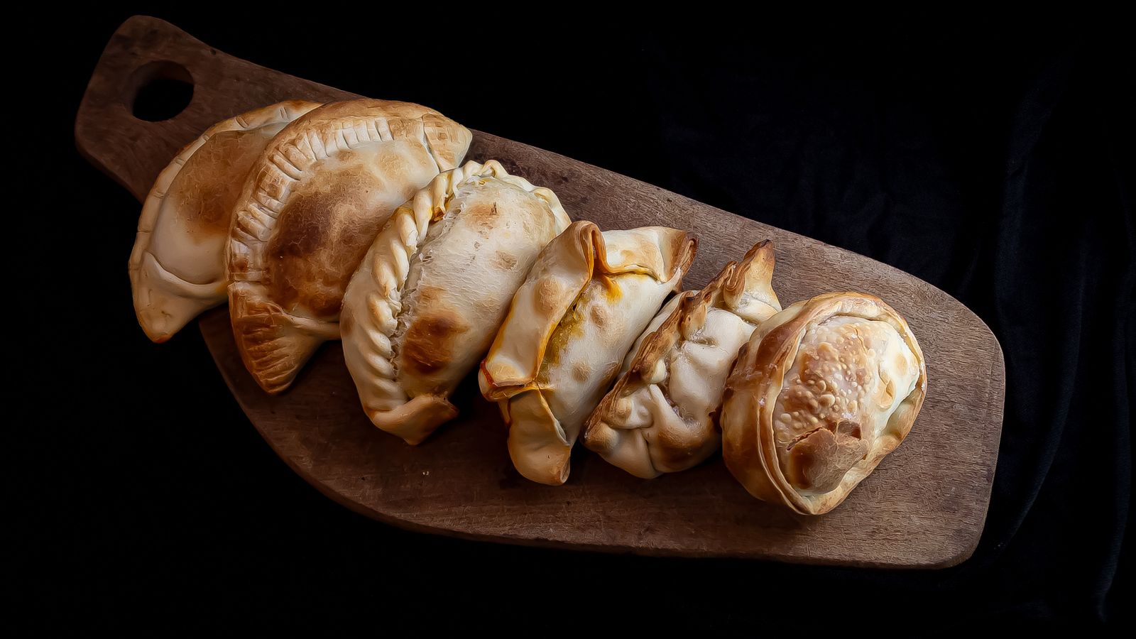 Freshly made empanadas arranged on a wooden board
