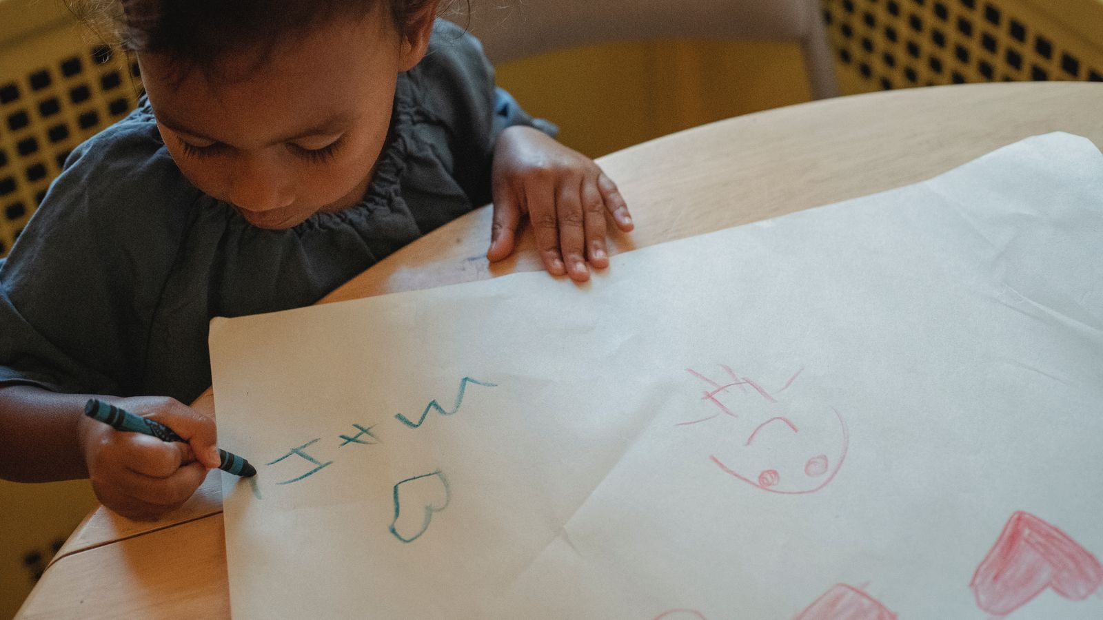 A child drawing with crayons on paper near a carpeted floor