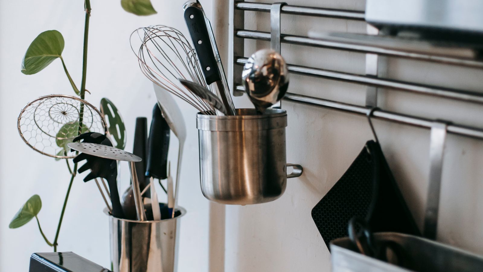 Hands cleaning a metal wire rack in a kitchen sink with soapy water