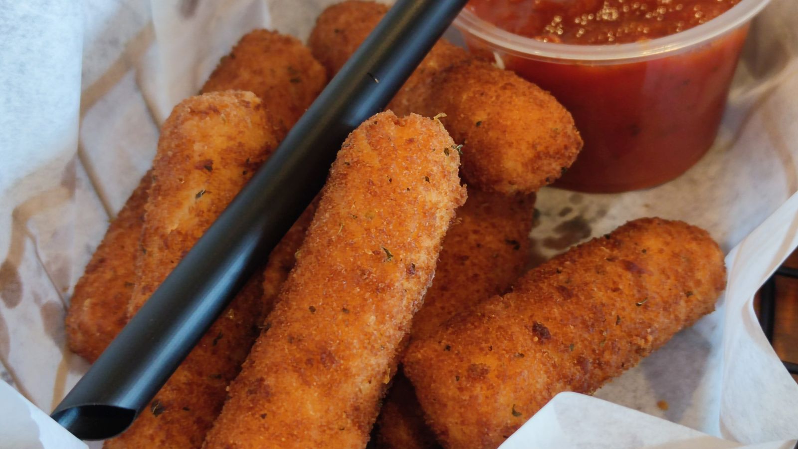 Golden crispy mozzarella sticks fresh out of an air fryer basket