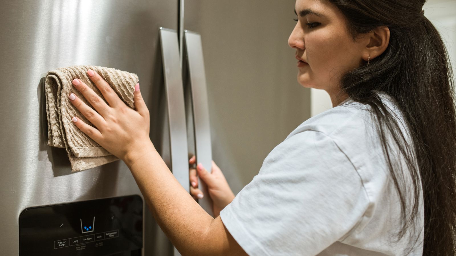 Hands scrubbing a nonstick air fryer basket in soapy water to remove cheese residue
