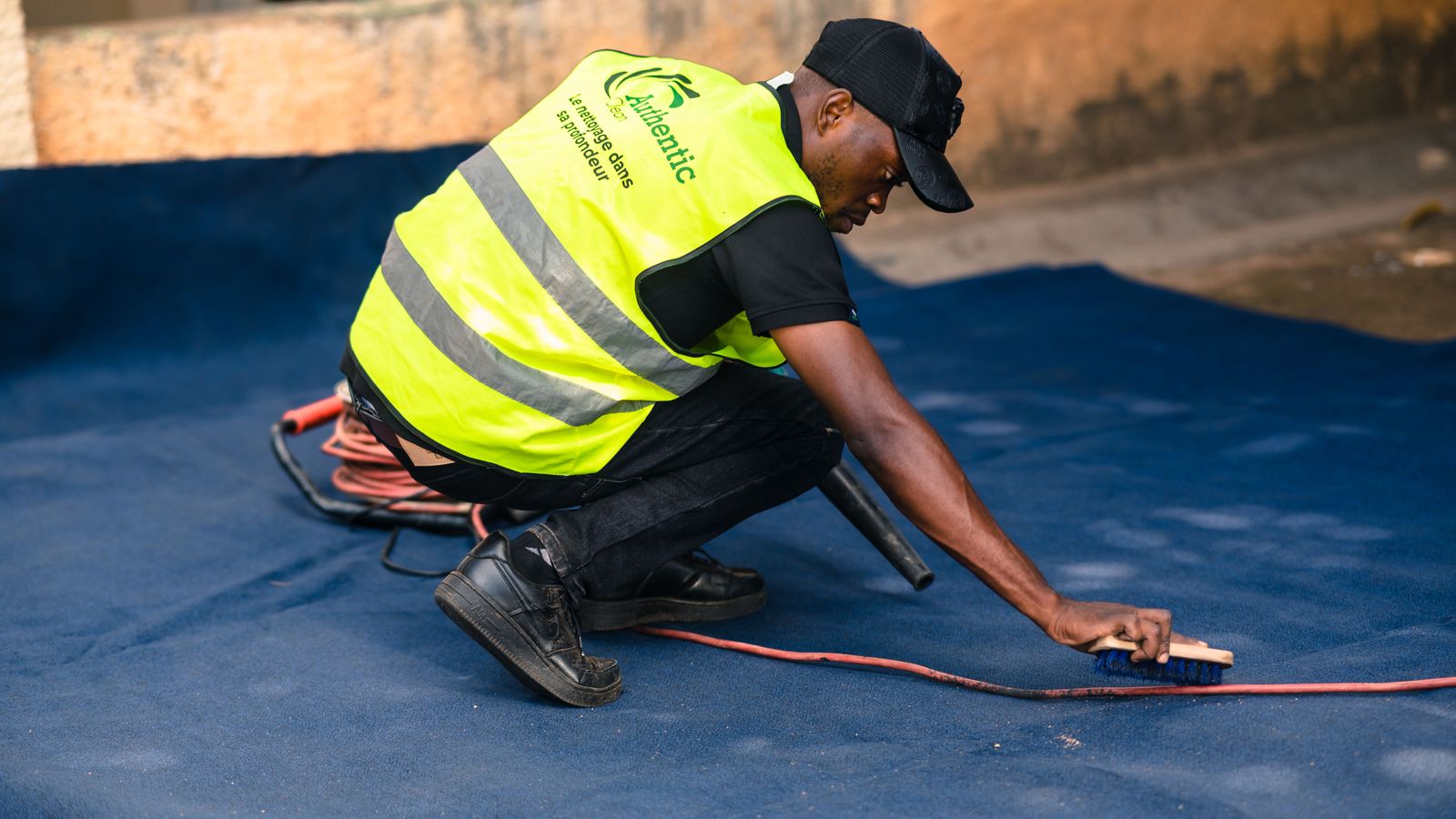 Worker using a stiff brush to groom and clean carpet fibers by hand