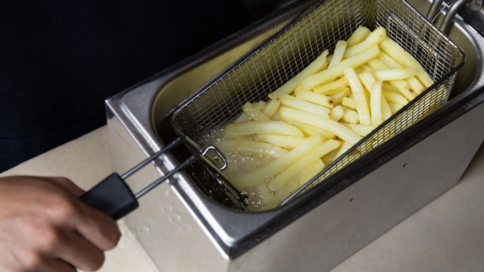 Person comparing two air fryer models on a countertop before buying