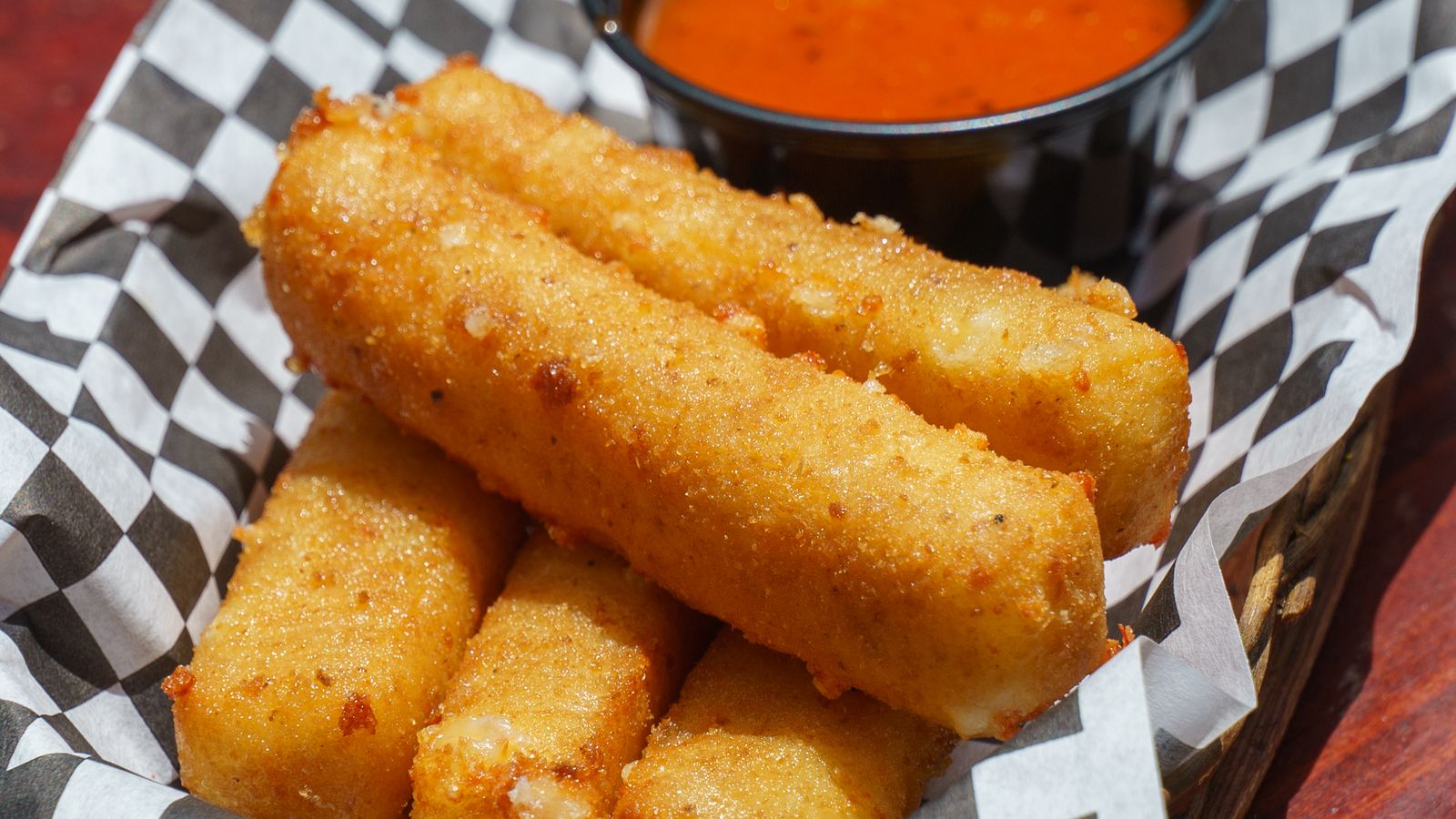 Crispy breaded mozzarella sticks with melted cheese on a serving plate