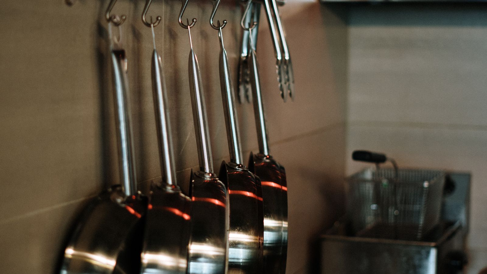 Stainless steel pans and kitchen accessories arranged neatly for an organized cooking and serving station