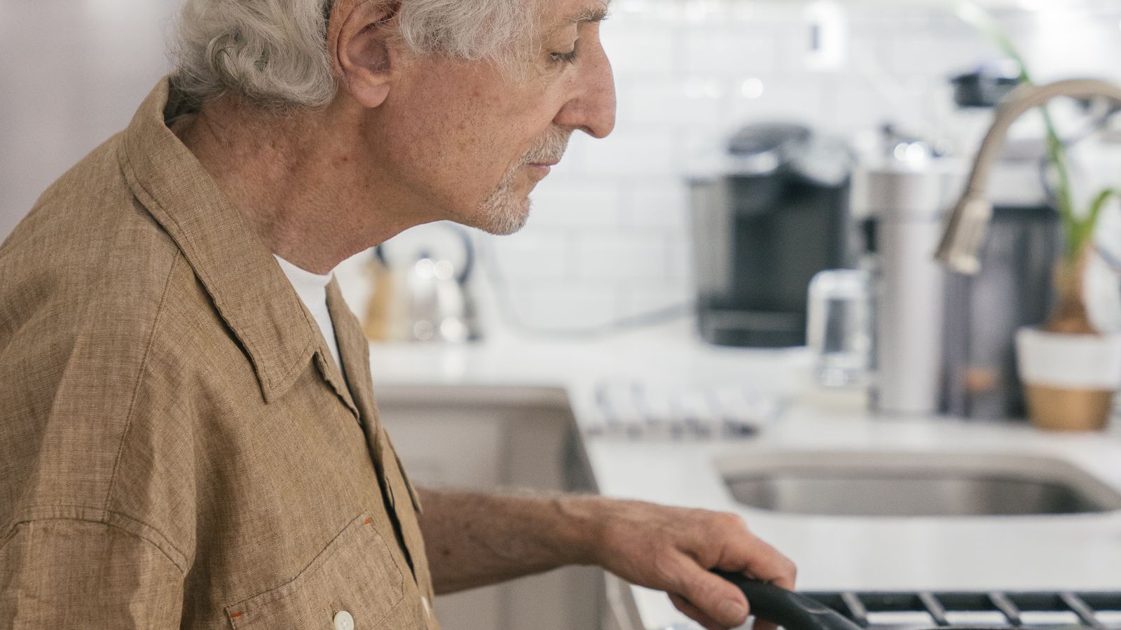 Senior man preparing a simple air fryer meal in a home kitchen