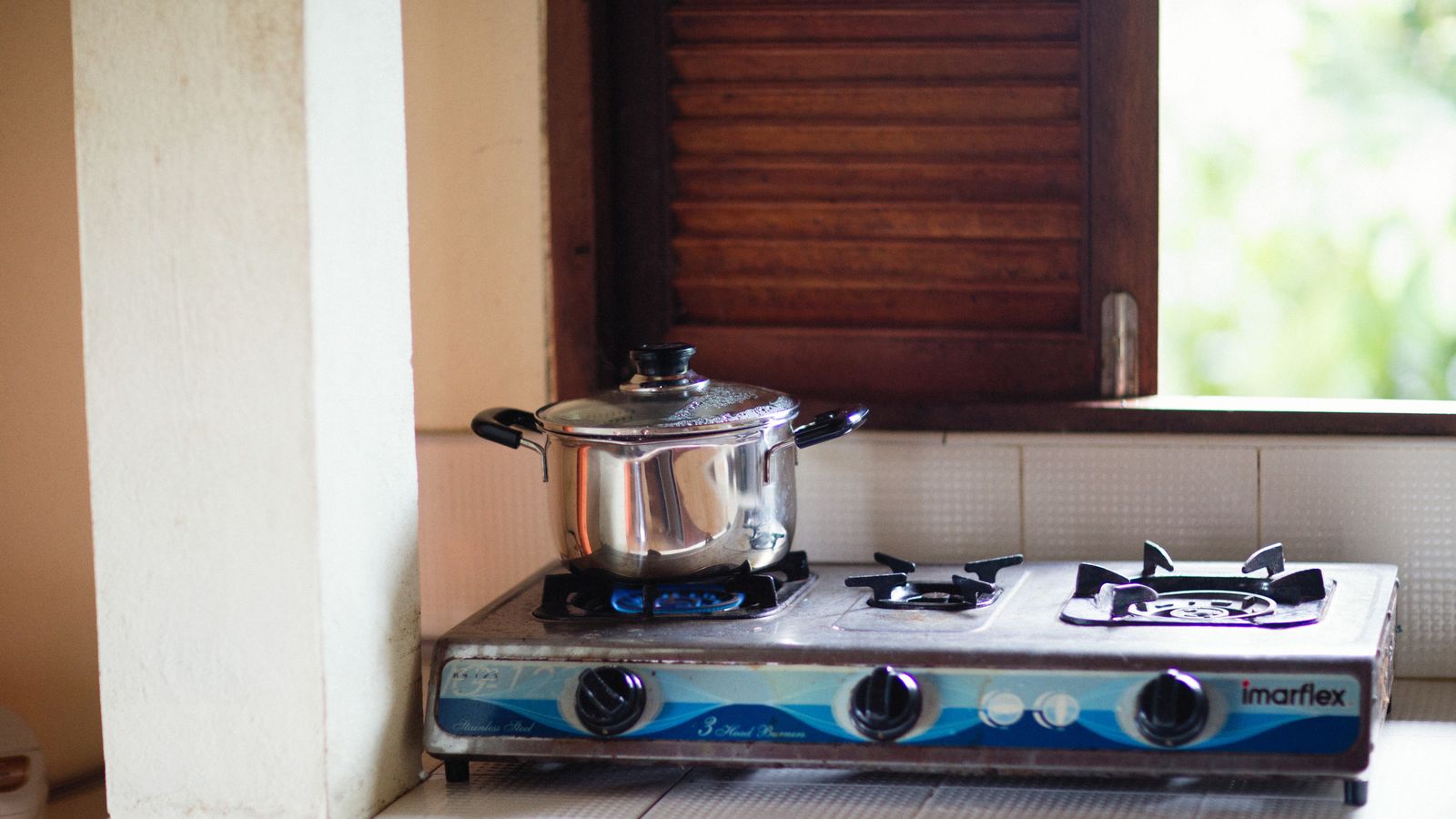 Stainless steel pot simmering on an open gas stove flame in a home kitchen