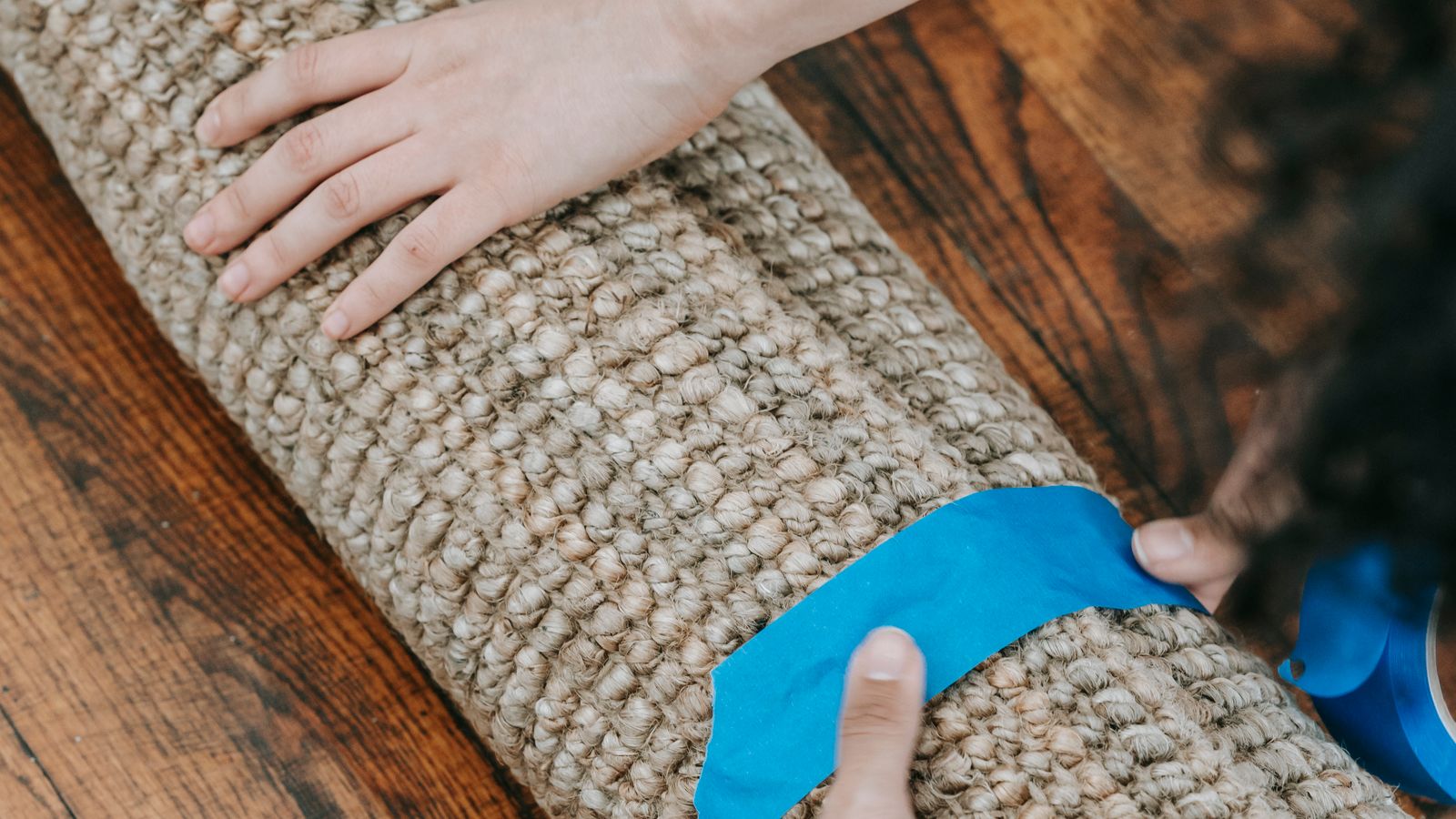 Hands installing carpet gripper strip along a room edge during a repair