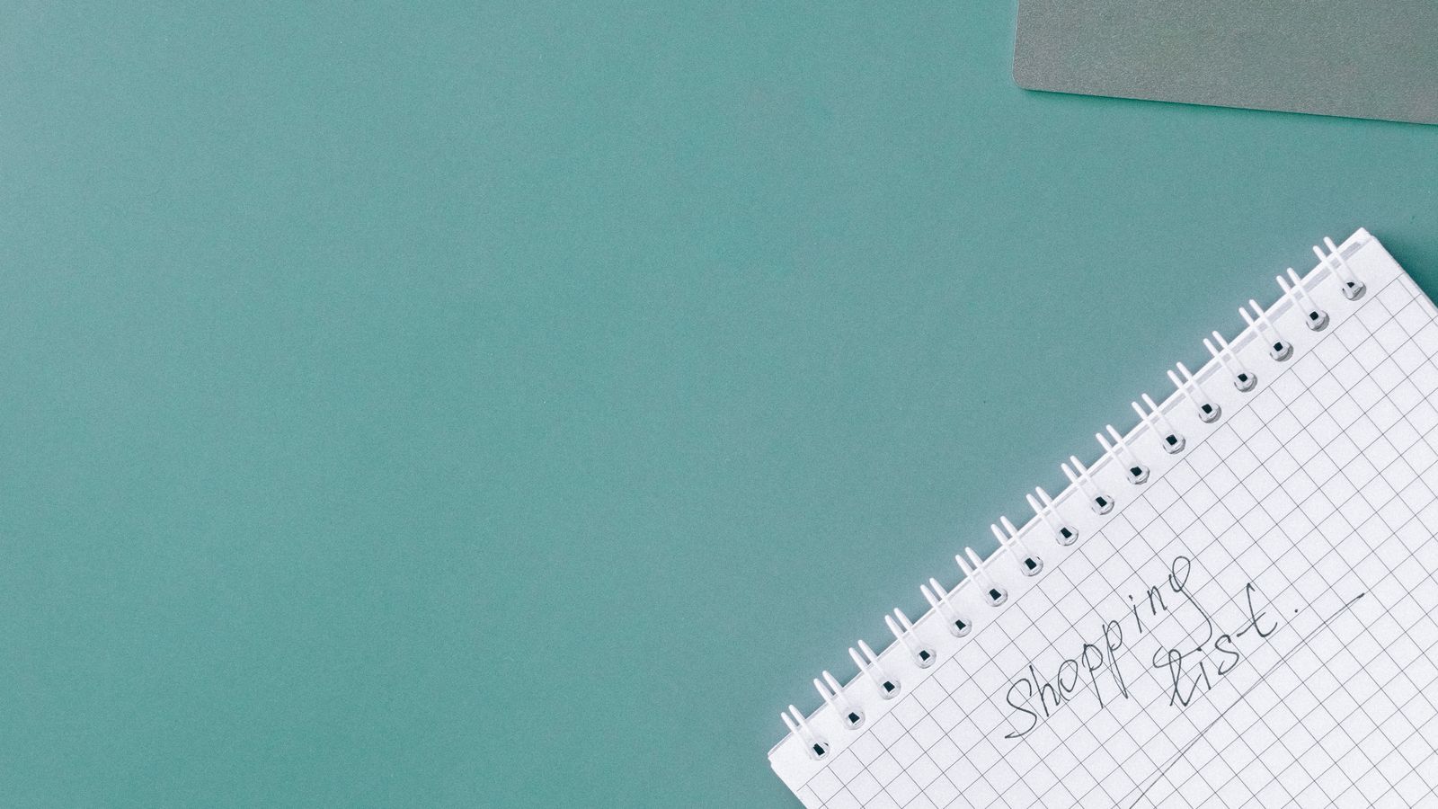 Handwritten budget shopping list next to a shopping cart for planning an air fryer purchase
