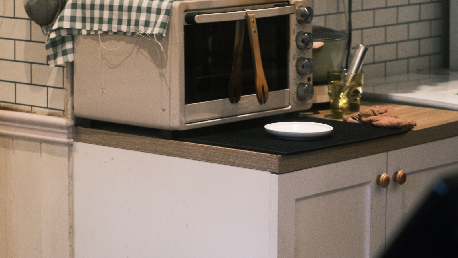 Countertop roaster oven sitting on a kitchen counter next to cooking utensils