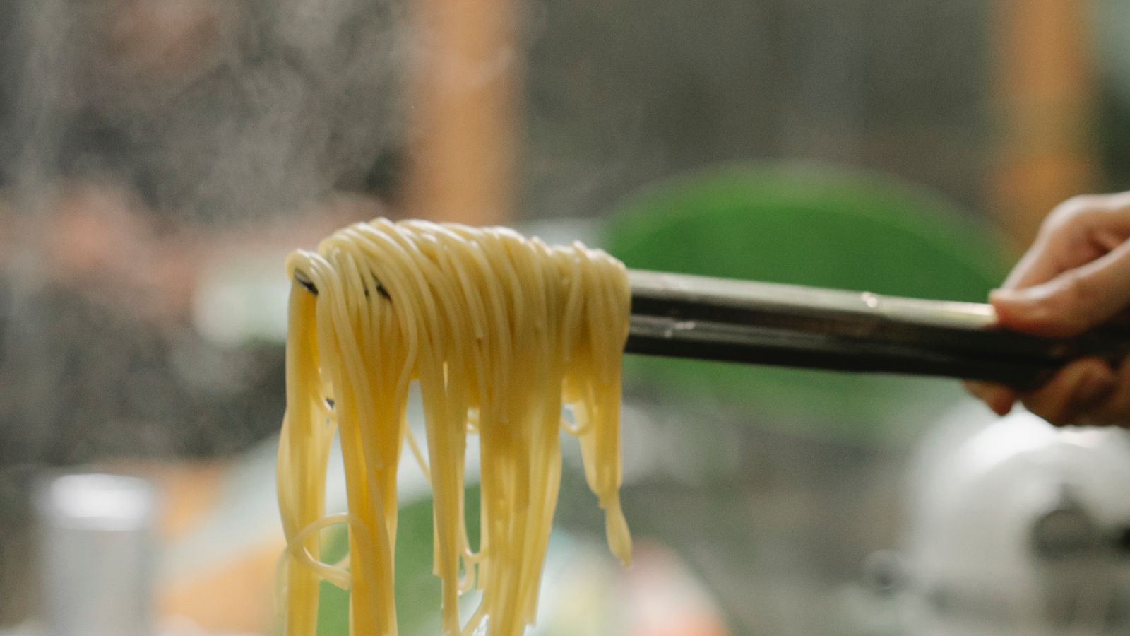 Using kitchen tongs to lift cooked food out of an air fryer basket