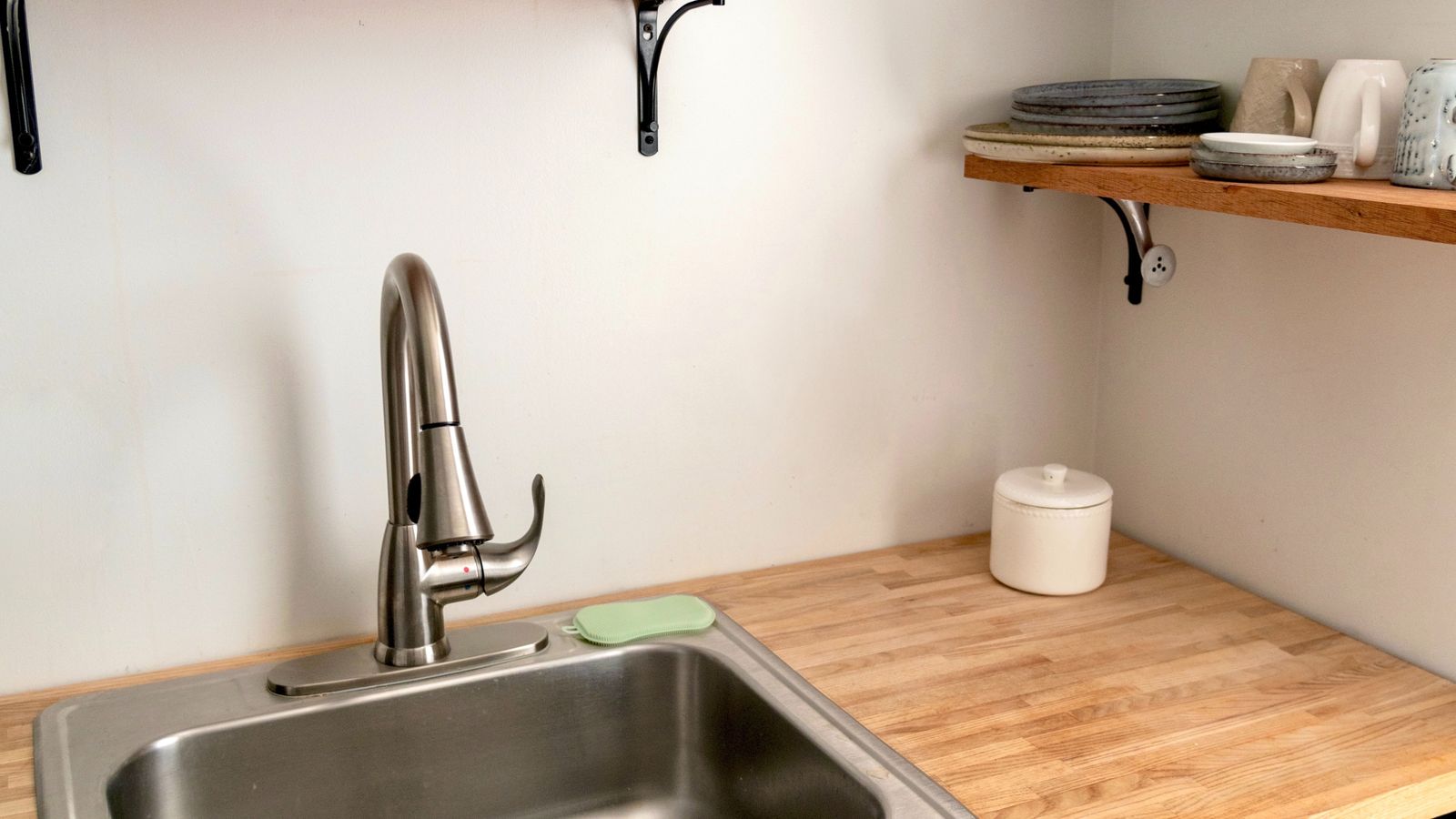 Clean kitchen shelf with stainless steel sink, an ideal small-space storage setup for a dorm air fryer