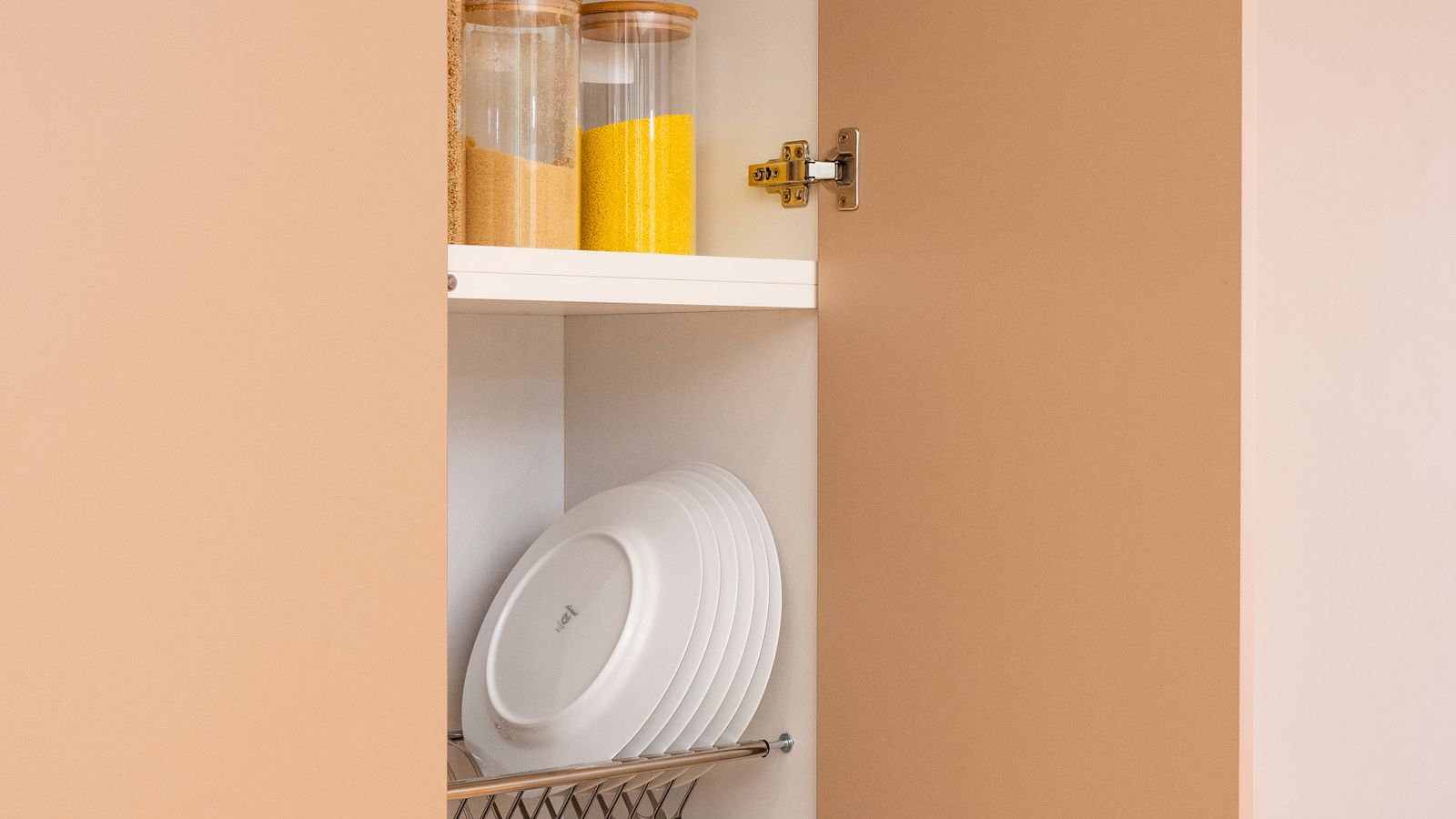 Organized kitchen cabinet with neatly stacked appliances and storage bins
