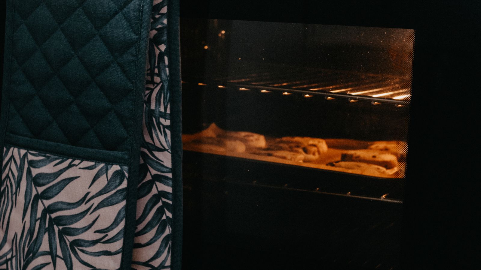 A pair of heat resistant oven gloves resting near a kitchen counter after use
