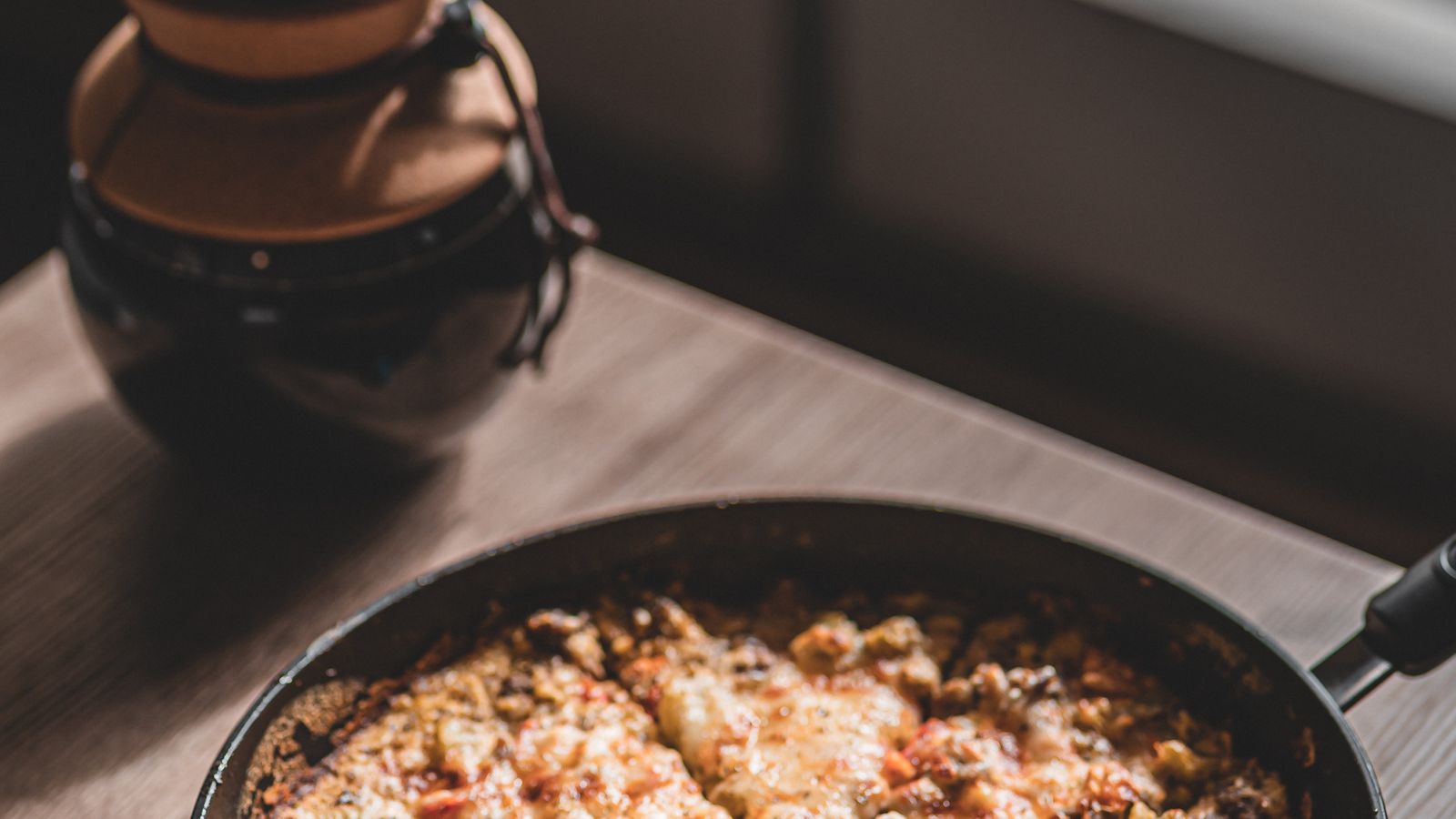 Golden brown pizza fresh out of a cast iron pan used in an air fryer