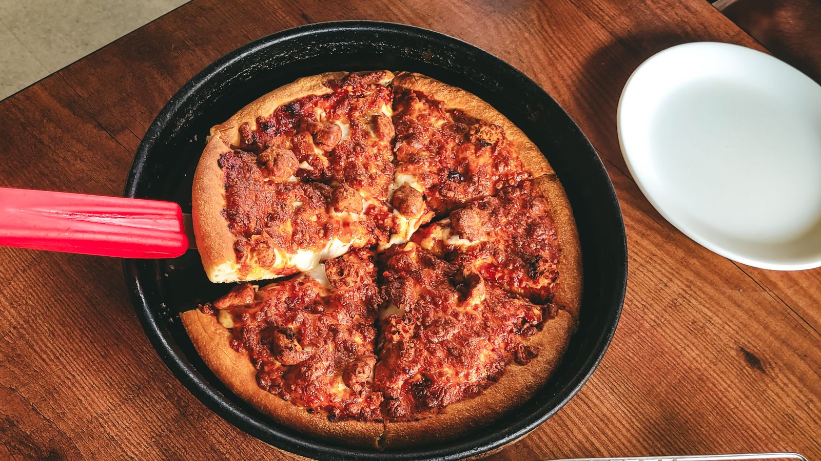 Pepperoni pizza baked on a dark metal pan showing browning and crust texture